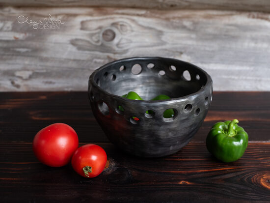 Melnās keramikas trauks ar dekoratīviem caurumiem