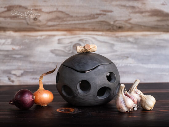 Melnās keramikas trauks ar caurumiem ķiplokiem