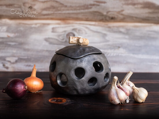 Melnās keramikas trauks ar caurumiem ķiplokiem