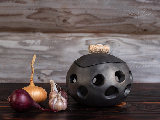 Melnās keramikas trauks ar caurumiem ķiplokiem